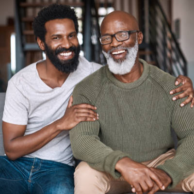 a son with his arms around his father, both smiling