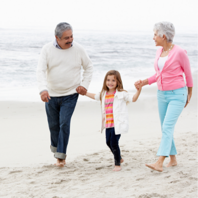 grandparents and grandchild walking down the beach