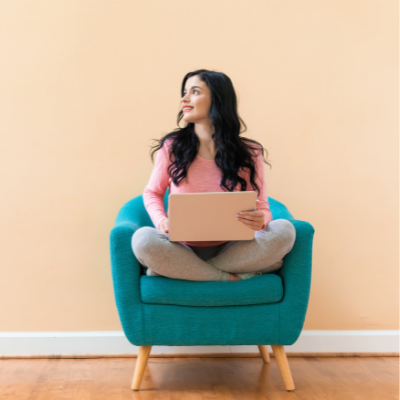 Woman sat cross legged on a chair with a laptop