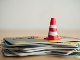 Small traffic cone on top of a stack of credit cards.