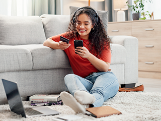 Girl listening to music with laptop, bank card and books.