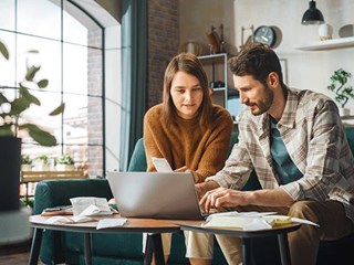 A couple sat looking at a laptop, trying to calculate tax bills