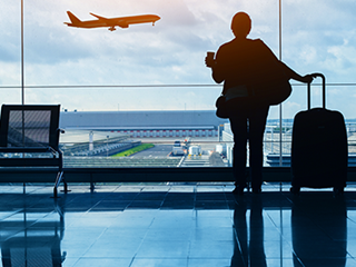 Person in airport lounge with luggage watching plane take off | Travel